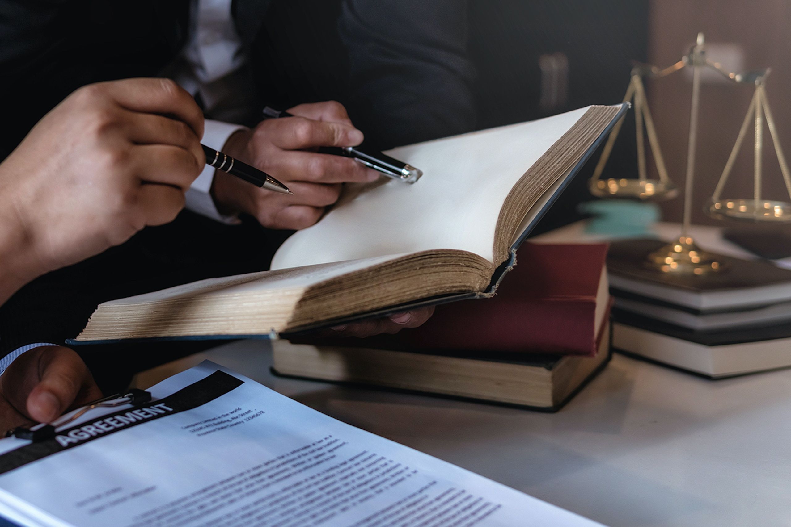 Close up of people analyzing a book in a law office