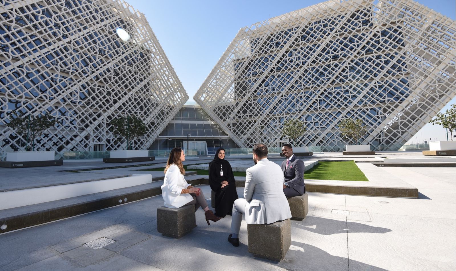 Four people in a circle, talking and smiling outside Ras Bufontas Office Building